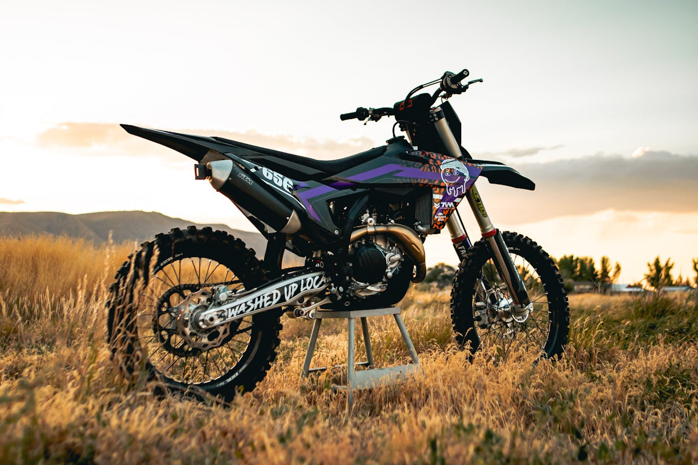 Motorcycle parked in a field with a sunset sky